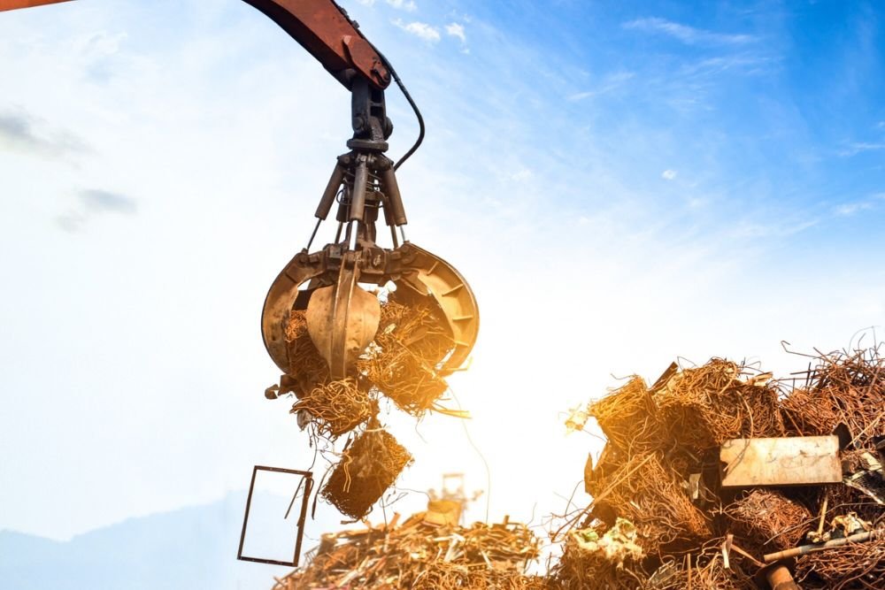 A large lifting machine handles a pile of metal, highlighting junk removal services in Aurora, CO.